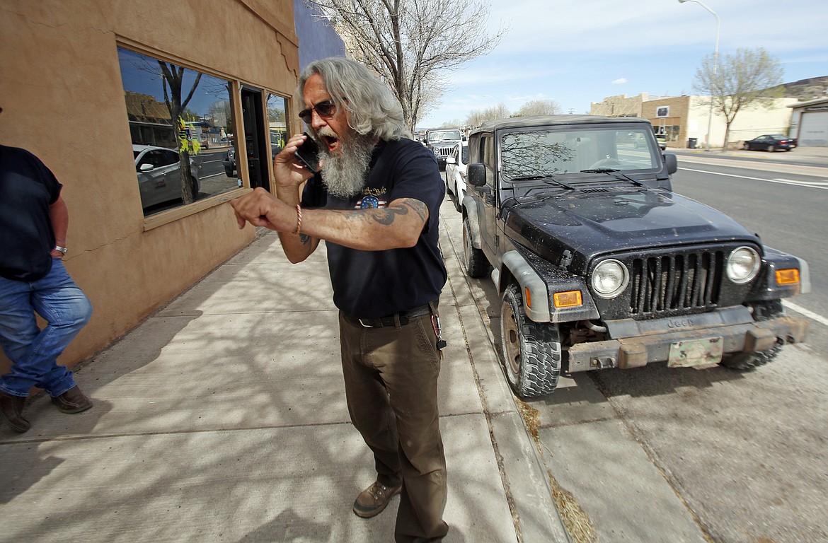 Grants Mayor Martin Hicks speaks to a news media outlet on the phone outside Loffler's Gun Etc in Grants, N.M., Monday, April 27, 2020. Hicks opened the city's businesses back up with an executive order, defying the Governor's orders. (Luis Sánchez Saturno/Santa Fe New Mexican via AP)