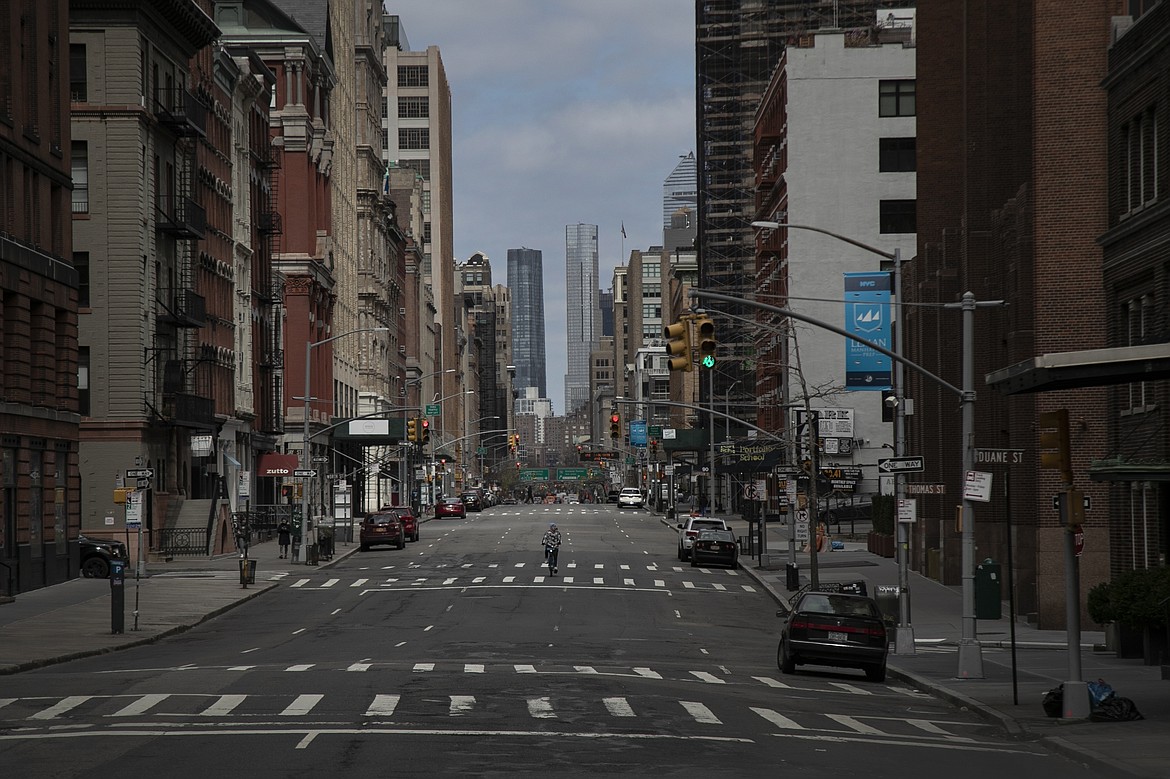A cyclist rides his bicycle down the middle of a main road in downtown New York, on Sunday, March 22, 2020. New York City's mayor prepared Sunday to order his city behind closed doors in an attempt to slow a pandemic that has swept across the globe and threatened to make the city of 8.5 million one of the world's biggest coronavirus hot spots. (AP Photo/Wong Maye-E)