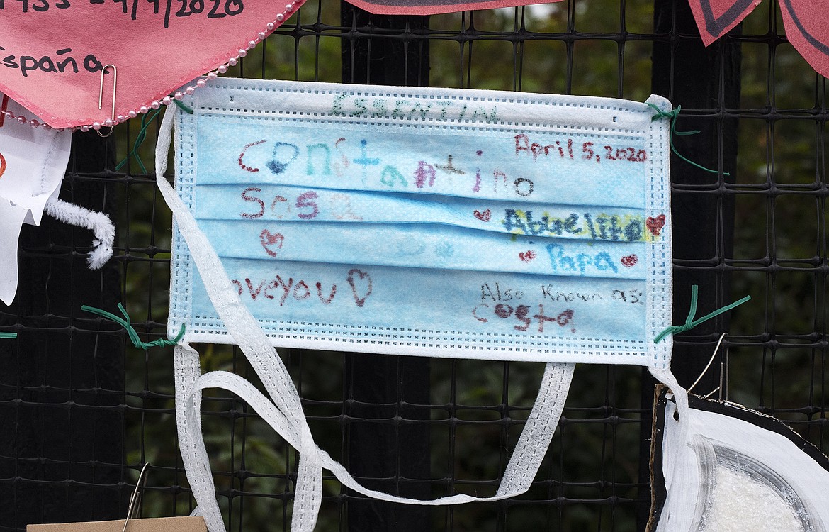 A fence outside Brooklyn's Green-Wood Cemetery is adorned with a surgical mask tribute Constantino Sosa, Thursday, May 28, 2020 in New York during the coronavirus pandemic. The memorial is part of the Naming the Lost project which attempts to humanize the victims. On Wednesday, the United States' official reported coronavirus death toll reached one hundred thousand. (AP Photo/Mark Lennihan)