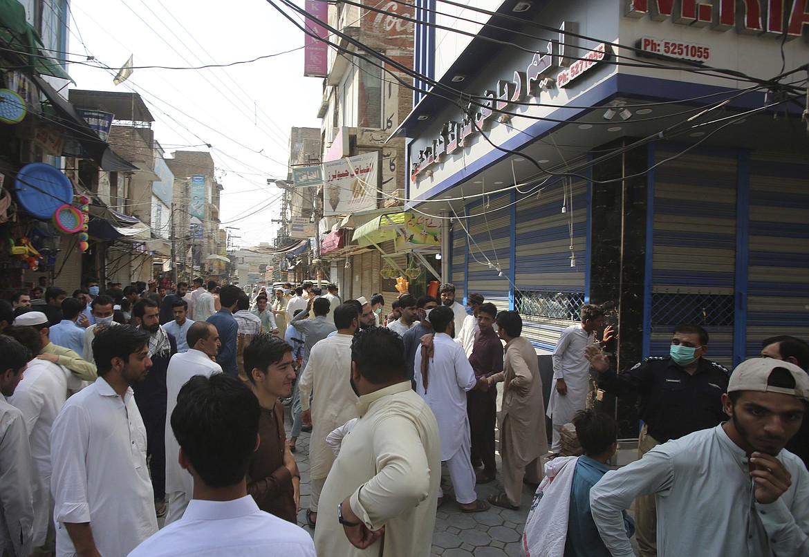 Shopkeepers stand stand outside their shops that were closed by authorities to help to control the spread of the coronavirus, in Peshawar, Pakistan, Monday, June 29, 2020. (AP Photo/Muhammad Sajjad)