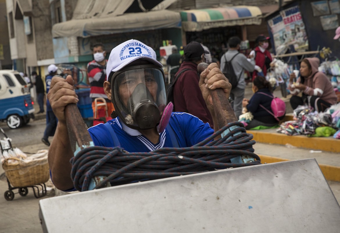 A man who works transporting merchandise for vendors and shoppers wears a mask due to the new coronavirus pandemic at a fish market in the Villa Maria del Triunfo district on the outskirts from Lima, Peru, Wednesday, May 27, 2020. (AP Photo/Rodrigo Abd)