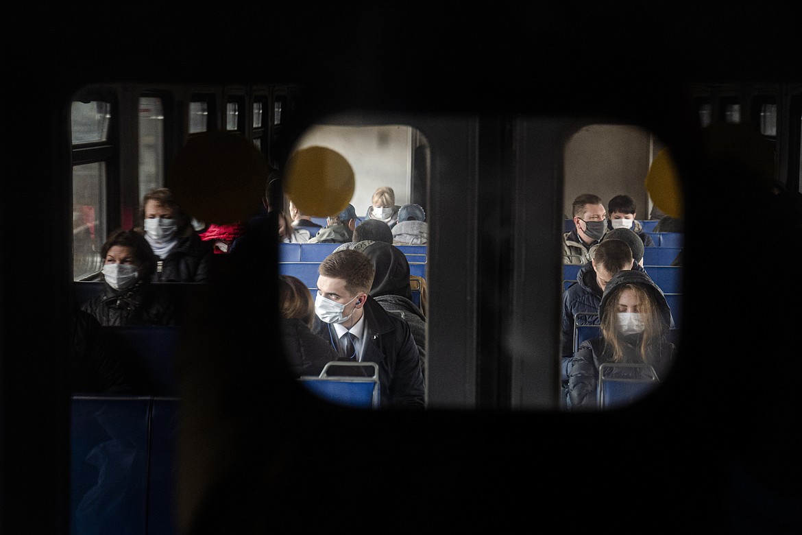 People wearing face masks to protect against coronavirus, ride a suburban train near Moscow, Russia, Thursday, April 16, 2020. Russian President Vladimir Putin has ordered most Russians to stay off work until the end of April as part of a partial economic shutdown to stymie the spread of the coronavirus. (AP Photo/Victor Berezkin)