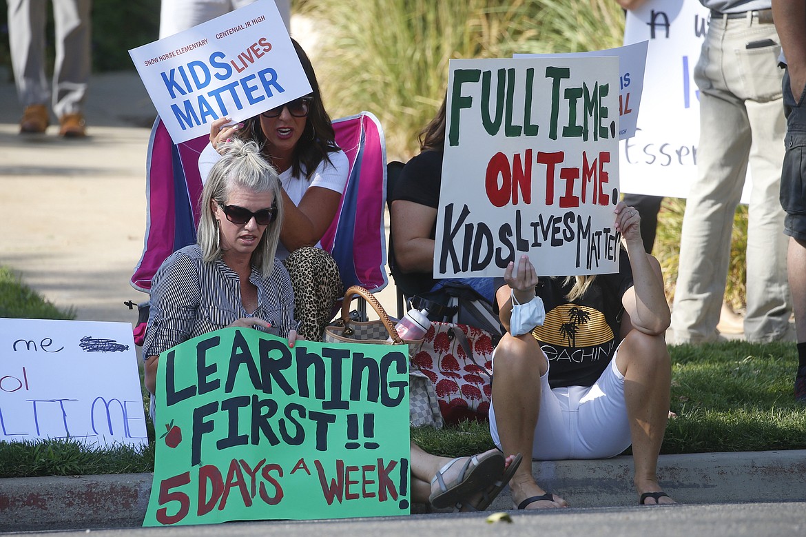Staci Patrick, left, protests with others in front of the Davis School District Office, Tuesday, Aug. 4, 2020, in Farmington, Utah. A group of parents protested the district's hybrid reopening plan because they would prefer their children to attend school five days a week. (AP Photo/Rick Bowmer)