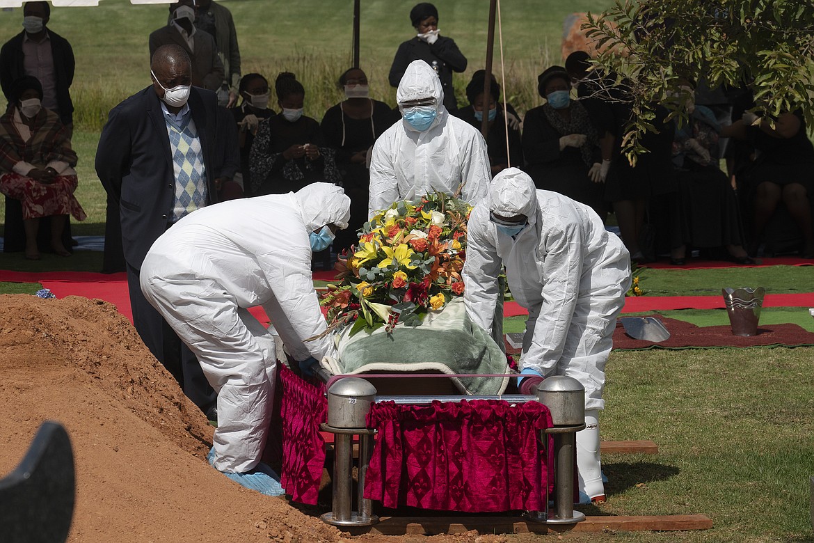 Pallbearers wearing full PPE suits lower in the grave the casket containing the remains of Benedict Somi Vilakasi for his burial ceremony at the Nasrec Memorial Park outside Johannesburg Thursday, April 16, 2020. Vilakasi, a Soweto coffee shop manager, died of Covid-19 infection in a Johannesburg hospital Sunday April 12 2020. South Africa is under a strict five-week lockdown in a effort to fight the Coronavirus pandemic.(AP Photo/Jerome Delay)