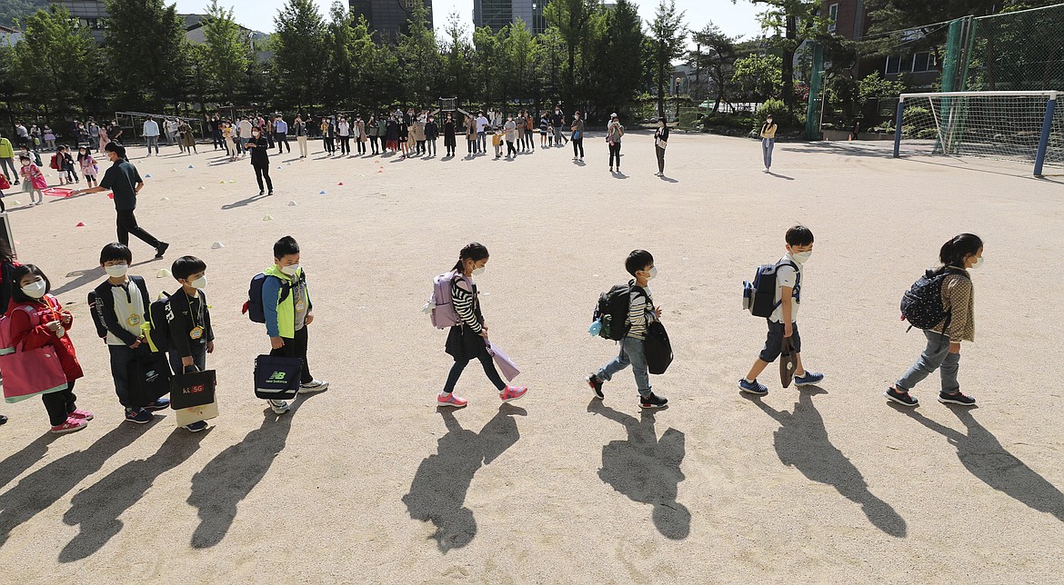 Students wearing face masks as a precaution against the new coronavirus, walk to their classrooms while maintaining social distancing after they attend the entrance ceremony at Chungwoon elementary school in Seoul, South Korea, Wednesday, May 27, 2020. More than 2 million high school juniors, middle school seniors, first- and second-grade elementary school children and kindergartners were expected to return to school on Wednesday. (Lee Jin-wook/Yonhap via AP)