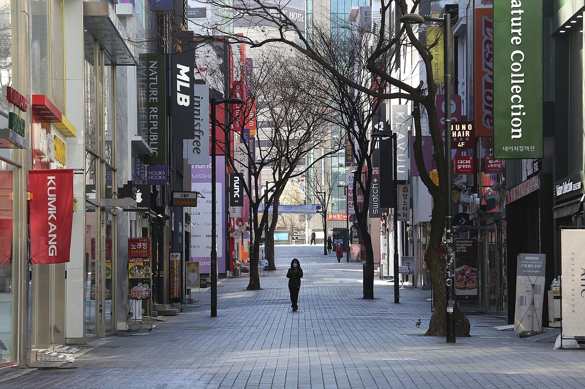 A woman wearing a face mask against the coronavirus walks along on a nearly empty shopping street in Seoul, South Korea, Sunday, March 22, 2020. For most people, the new coronavirus causes only mild or moderate symptoms, such as fever and cough. For some, especially older adults and people with existing health problems, it can cause more severe illness, including pneumonia. (AP Photo/Ahn Young-joon)