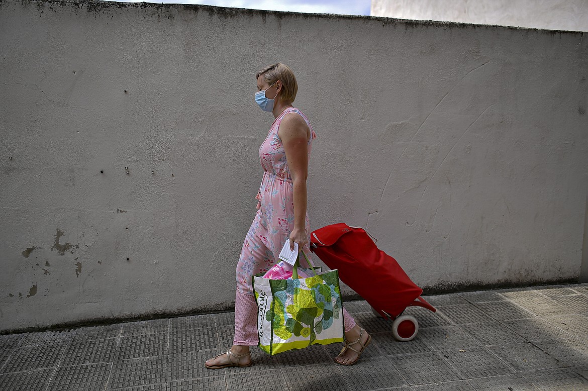 Alina Ghirean, 36 years old, wears face mask to prevent the coronavirus pulls her trolley after receiving a pack of foods from charity foundation Caritas, to last the next two weeks, in Estella, around 38 kms (23, 61 miles) from Pamplona, northern Spain, Wednesday, July 1, 2020. Spain is beginning to suffer an economic crisis due to the coronavirus pandemic.(AP Photo/Alvaro Barrientos)