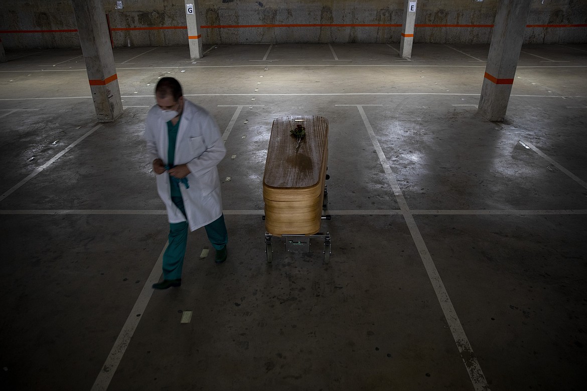Head mortician Jordi Fernandez, walks next to the coffin of the last COVID-19 victim stored at an underground parking garage that was turned into a morgue, at the Collserola funeral home in Barcelona, Spain Sunday May 17, 2020. A funeral home in Barcelona has closed a temporary morgue it had set up inside its parking garage to keep the victims of the Spanish city's coronavirus outbreak. The last coffin was removed and buried on Sunday. In 53 days of use, the temporary morgue has held more than 3,200 bodies. (AP Photo/Emilio Morenatti)