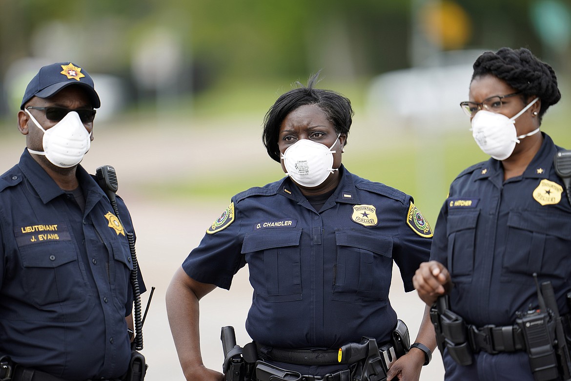Law enforcement officers wear masks while working at a newly opened free drive through Covid-19 testing site provided by United Memorial Medical Center Thursday, April 2, 2020, in Houston. The new coronavirus causes mild or moderate symptoms for most people, but for some, especially older adults and people with existing health problems, it can cause more severe illness or death. (AP Photo/David J. Phillip)