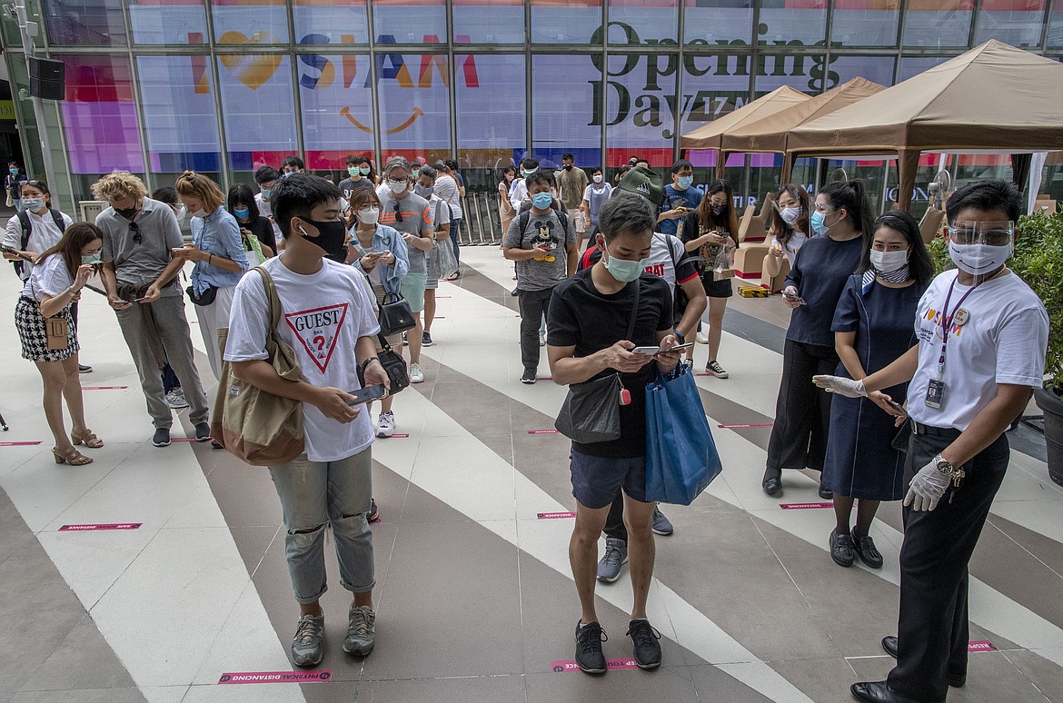 Patrons stand maintaining a physical distance at the entrance of the upmarket shopping mall Siam Paragon in Bangkok, Thailand, Sunday, May 17, 2020. Thai authorities allowed department stores, shopping malls and other businesses to reopen from Sunday, selectively easing restrictions meant to combat the coronavirus. (AP Photo/ Gemunu Amarasinghe)