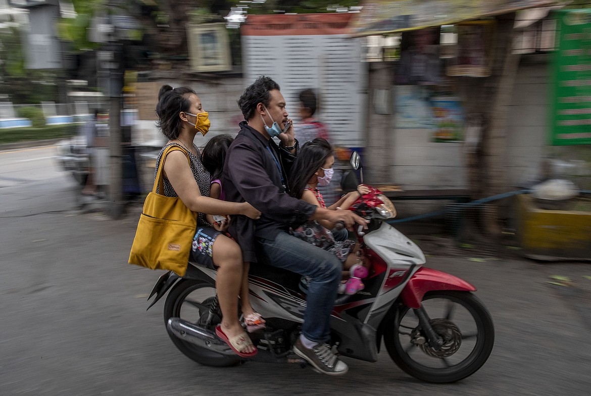 A Thai family of four, wearing face masks travel in a motorbike in Bangkok, Thailand, Thursday, April 16, 2020. A month-long state of emergency remain enforced in Thailand to allow its government to impose stricter measures to control the coronavirus that has infected hundreds of people in the Southeast Asian country. (AP Photo/Gemunu Amarasinghe)