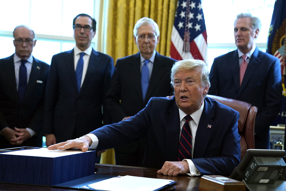 President Donald Trump speaks before he signs the coronavirus stimulus relief package in the Oval Office at the White House, Friday, March 27, 2020, in Washington. Listening are from left, Larry Kudlow, White House chief economic adviser, Treasury Secretary Steven Mnuchin, Senate Majority Leader Mitch McConnell, R-Ky., and House Minority Leader Kevin McCarty of Calif. (AP Photo/Evan Vucci)