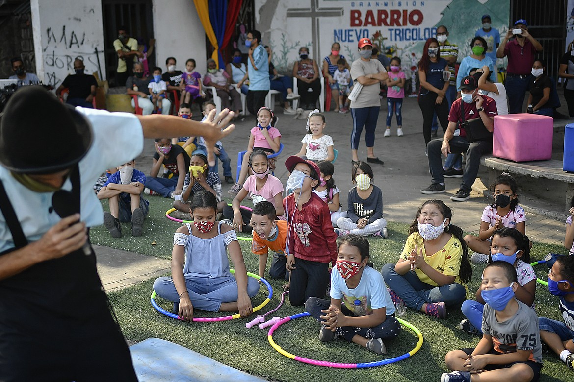 Children watch a performance by the National Circus Foundation of Venezuela at the San Juan neighborhood of Caracas, Venezuela, Saturday, May 9, 2020. The circus also does live stream performances at the National Caracas theater during the lockdown to prevent the the spread of the new coronavirus . (AP Photo/Matias Delacroix)