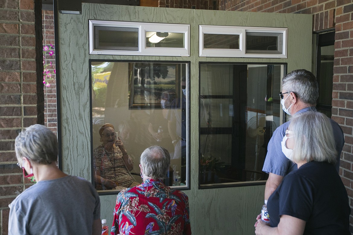 In this photo taken on Friday, June 26, 2020, from front left to right, Susan, Robert, Terry and Richard Lounsbury visit with Virginia Hathaway, 92, through the Chatter Box, a new feature at the Living Care Retirement Community in Yakima, Wash. The Chatter Box is a new effort to help residents safely see their families during the coronavirus pandemic. (Amanda Ray/Yakima Herald-Republic via AP)