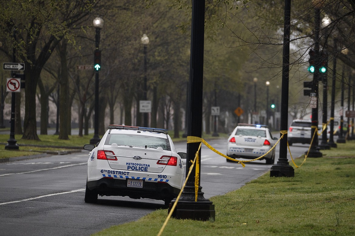 Washington D.C. Metropolitan Police vehicles parks along an empty Independence Avenue and behind yellow police tape near the Tidal Basin and cherry blossoms, in Washington, Monday, March 23, 2020. As Washington, D.C. continues to work to mitigate the spread of the coronavirus (COVID-19), Mayor Muriel Bowser extended road closures and other measures to restrict access to the Tidal Basin, a main tourist attraction. (AP Photo/Carolyn Kaster)