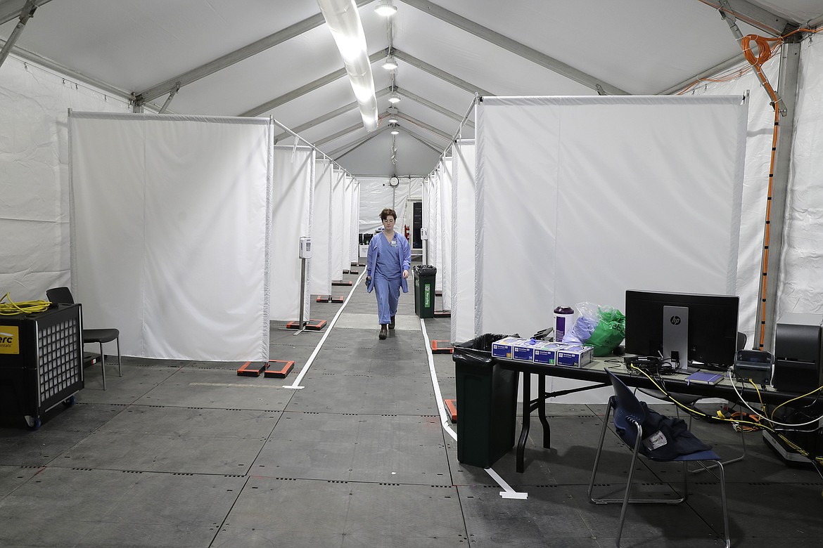 Forest Gauthier, an emergency services medical assistant, walks through a tent set up outside the Emergency Department at the Harborview Medical Center before it opened for patients, Thursday, April 2, 2020, in Seattle. The tent, which was recently put in place, is used to examine walk-up and other patients who arrive at the emergency room with respiratory symptoms possibly related to the new coronavirus. (AP Photo/Ted S. Warren)