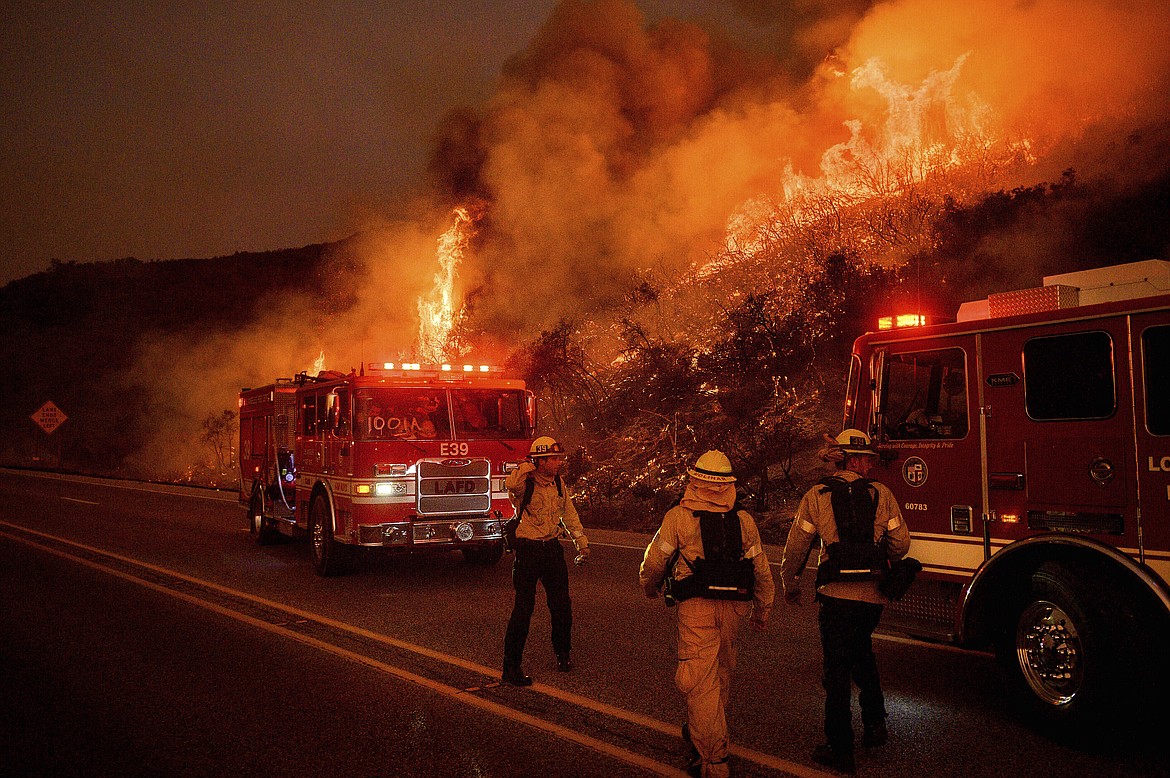 FILE - In this Nov. 26, 2019, file photo, firefighters battle the Cave Fire as it flares up along Highway 154 in the Los Padres National Forest above Santa Barbara, Calif. The outbreak of the coronavirus is making the U.S. Forest Service and others change strategies for fighting wildfires, as the need for isolation and social distancing comes into play against the necessity of having firefighters work and live closely together. (AP Photo/Noah Berger, File)