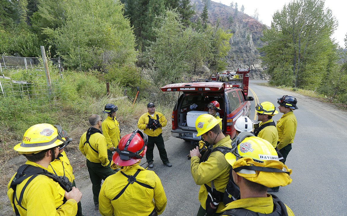 FILE - In this Aug. 21, 2015, file photo, firefighters from several King County agencies gather for a briefing while fighting a wildfire near Twisp, Wash. The outbreak of the coronavirus is making the U.S. Forest Service and others change strategies for fighting wildfires, as the need for isolation and social distancing comes into play against the necessity of having firefighters work and live closely together. (AP Photo/Ted S. Warren, File)
