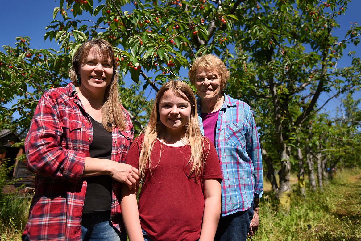 Denise Bowman Wermer, her daughter Ayla and her mother Marilyn Bowman stroll through the cherry trees as Bowman Orchards celebrates its 100th year in 2020. (Jeremy Weber/Daily Inter Lake)