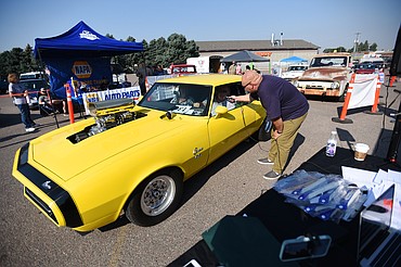 Monte Klindt, right, co-owner of Performance Heating & Air in Evergreen and a co-organizer of Kruise Kalispell, speaks with Donny Stevens as he drives his 1968 Chevrolet Camaro SS through the Evergreen Show ’N Shine virtual car show at Conlin’s Furniture on Saturday.  (Casey Kreider/Daily Inter Lake)
