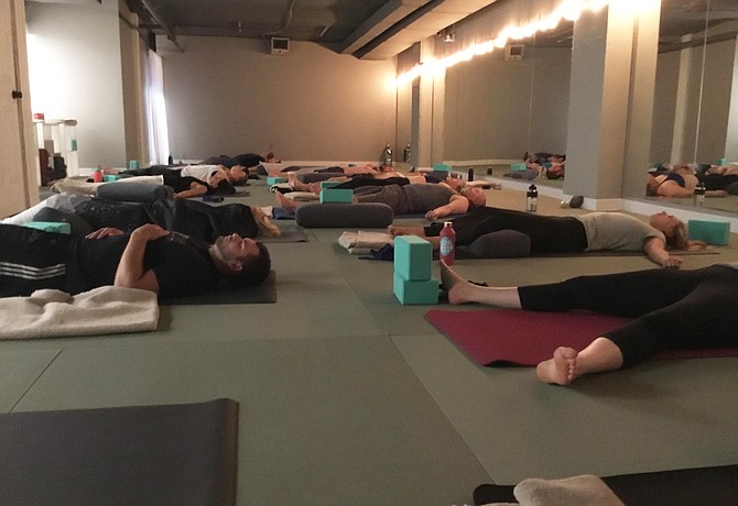 A class relaxes in shavasana, or corpse pose, at the end of a session at The Path Hot Yoga. Aside from yoga classes, The Path offers team building sessions, corporate wellness programs and breathe workshops to give patrons a variety of options to meet their needs.