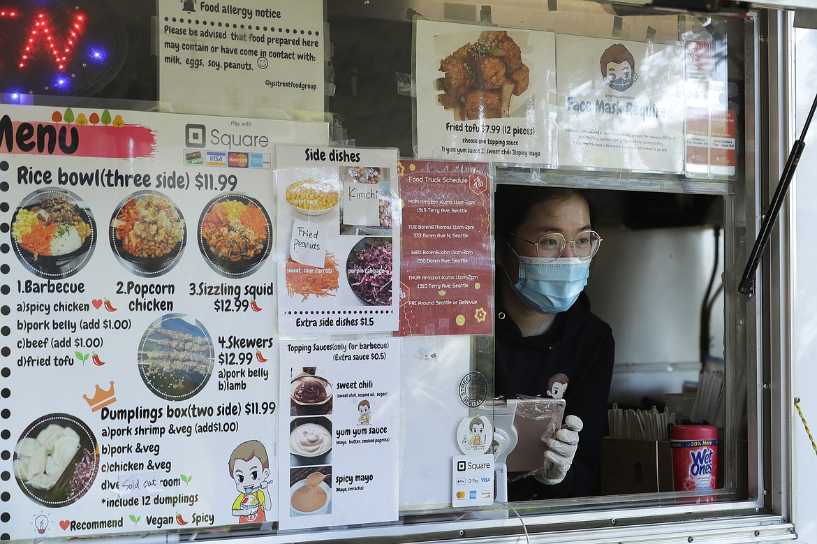 Yuli Shen takes an order as she works in her YS Street Food food truck, Monday, Aug. 10, 2020, near the suburb of Lynnwood, Wash., north of Seattle. Long seen as a feature of city living, food trucks are now finding customers in the suburbs during the coronavirus pandemic as people are working and spending most of their time at home. (AP Photo/Ted S. Warren)