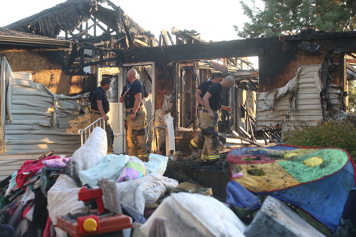 Firefighters look over the scene of Friday's blaze on N. Kaniksu Street in Post Falls that destroyed two homes.