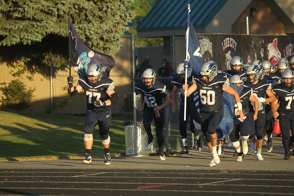 MARK NELKE/Press
Logan Parson (77) and Camdyn Martindale (50) lead the Lake City Timberwolves onto the field before the high school football season opener vs. the Lakeland Hawks at Lake City High. Lake City won 26-20. See story/B1