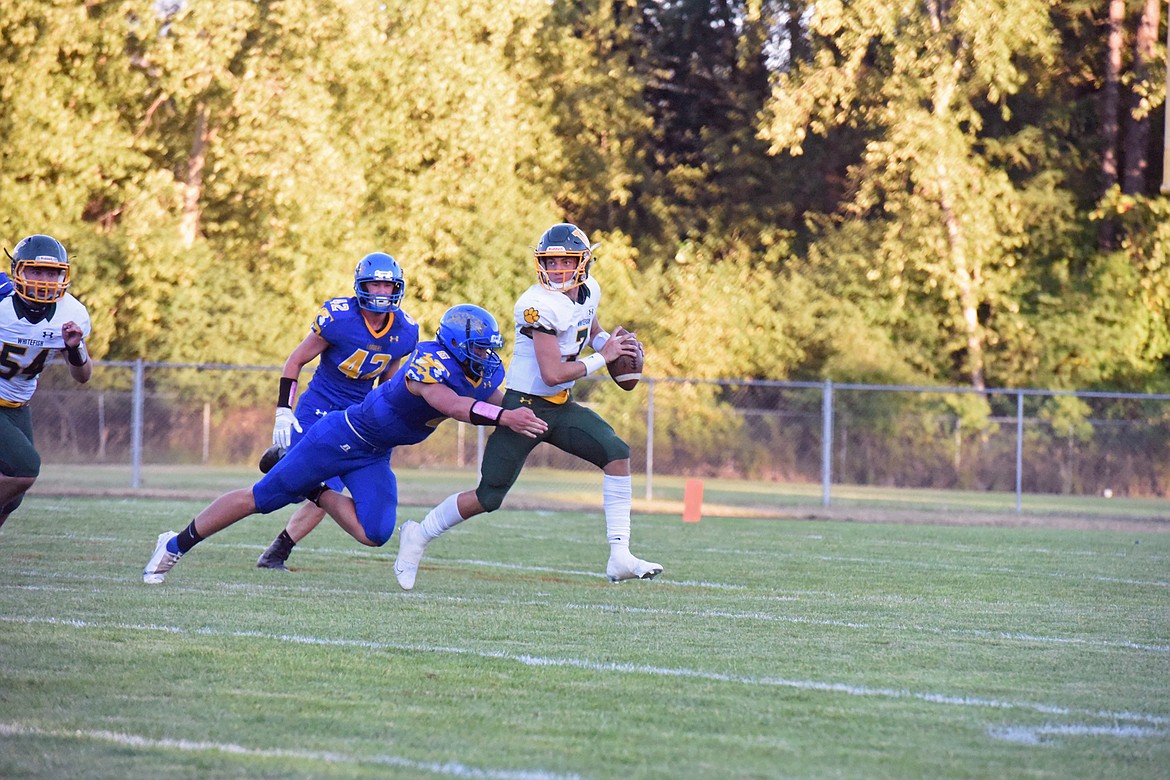 Whitefish quarterback Fynn Ridgeway keeps his cool as he looks to make a pass in tight coverage against the Loggers in Libby Friday night. (Derrick Perkins/The Western News)