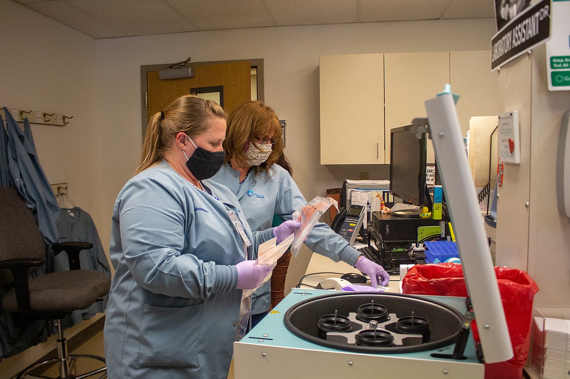 Shawn Dodge, right, processes the specimens and associated medical records, generating a barcode to attach to the test which helps keep staff and health officials keep track of coronavirus transmission. Stephanie Sieloff, left, then takes a test to the diagnostic tools used to detect coronavirus antigens.
