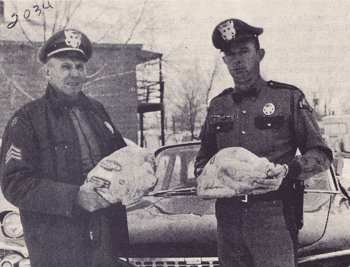 Sgt. A. L. Hunt, left, and Austin Jerpe from the Columbia Basin detachment of the Washington State Patrol give away turkeys around the holiday season to families in need in the 1960s.