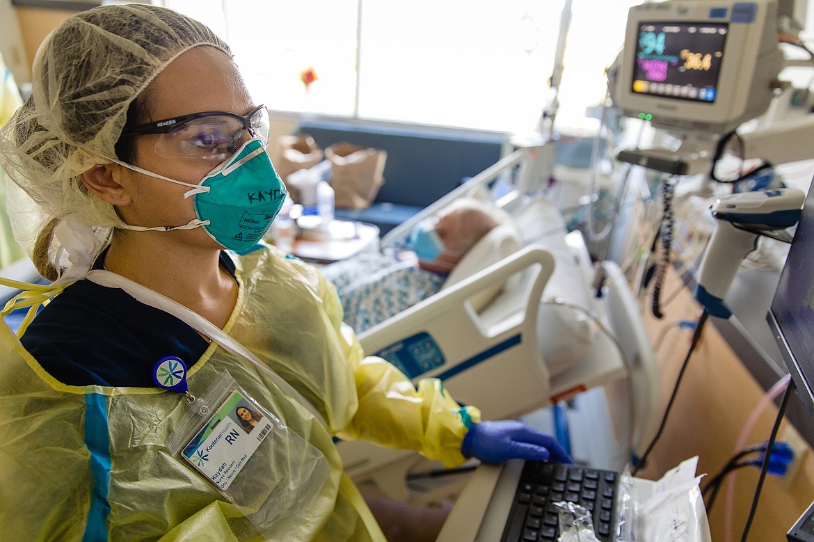 Nurse Kaydah Parker charts at the computer while caring for her patient. As part of her personal protective equipment, Kaydah is wearing eye protection, an N-95 respirator, gown and gloves. While on the unit, she will wear her gown, mask and eye protection continuously. She changes her gloves with each patient encounter.