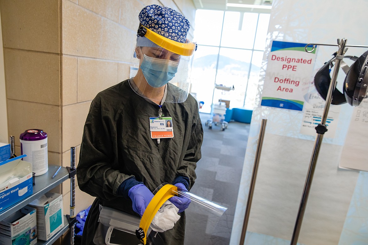 3 East charge nurse Stephanie Hall cleans a face shield with special disinfecting wipes.