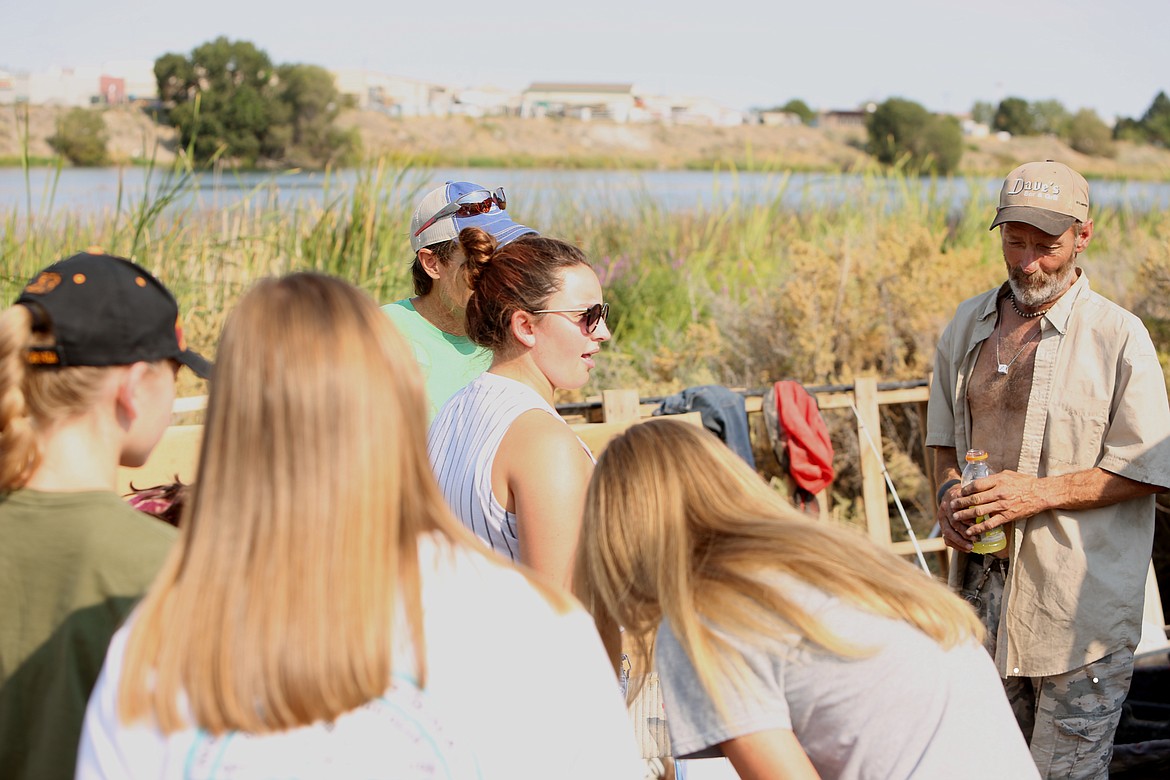 At the second camp they visited that morning, Emma Roth, center, joins pastor Mark Roeber in talking with "Cowboy," right, as many of the other kids cradle his small puppies.