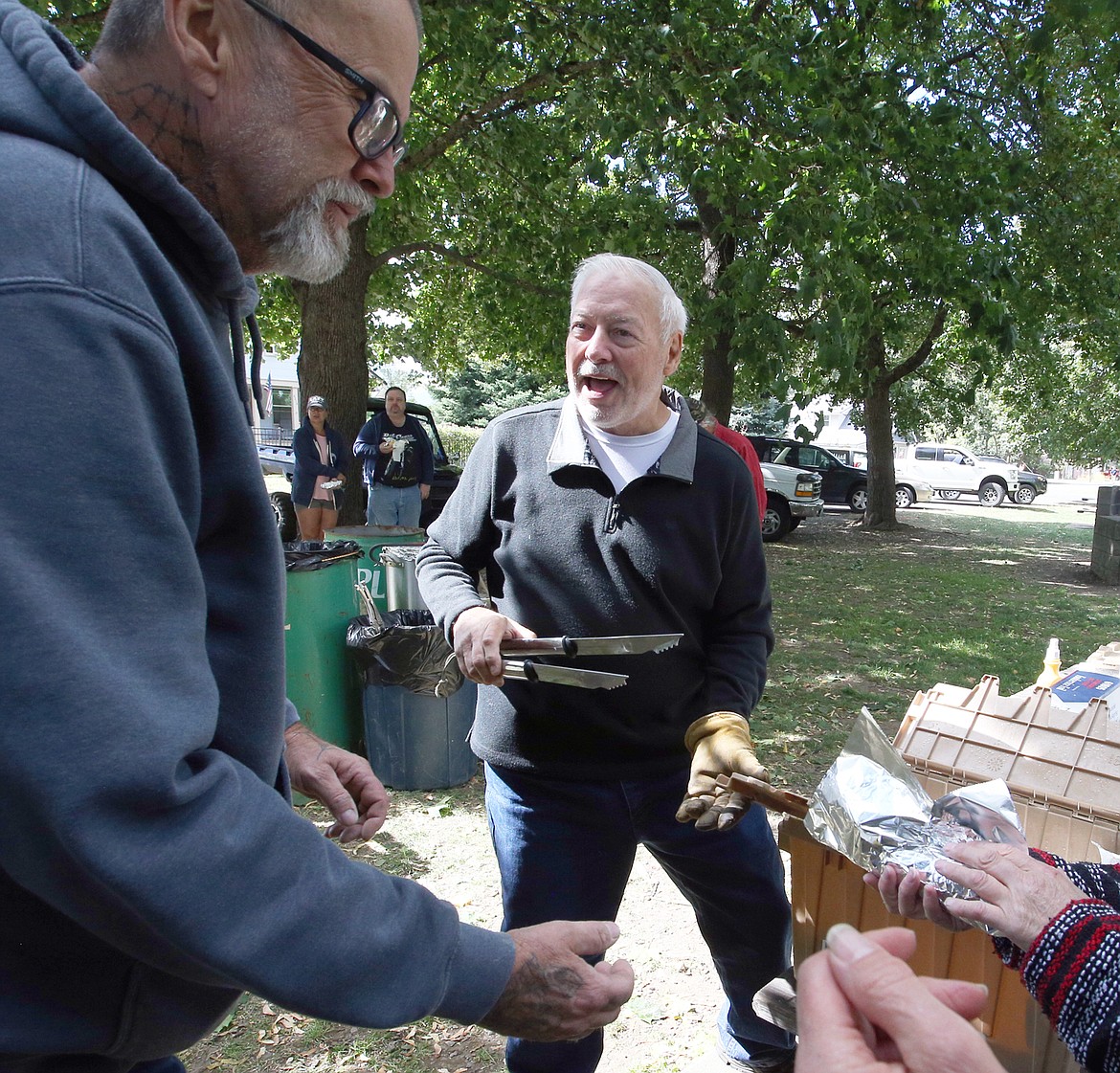 Mike Barham, VFW Post 1473 senior vice commander, smiles as he hands out corn on the cobb in  Spirit Lake City Park Monday.