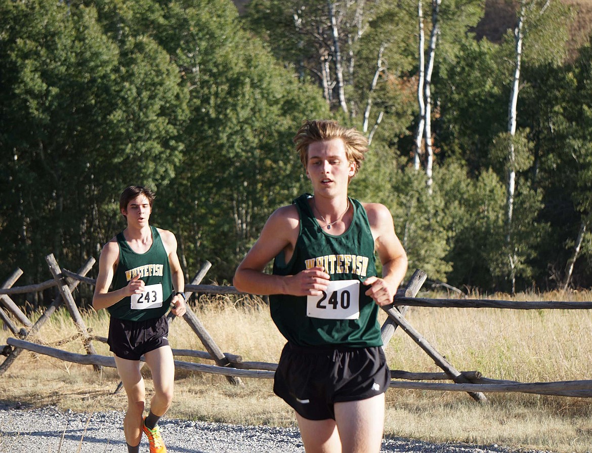 Whitefish’s Aidan Calaway (240) leads Barrett Garcia on the final mile of the cross country course last week in Eureka. (Matt Weller photo)