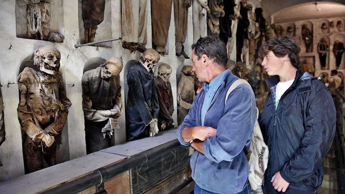 Visitors viewing mummies in the catacombs of Rome.