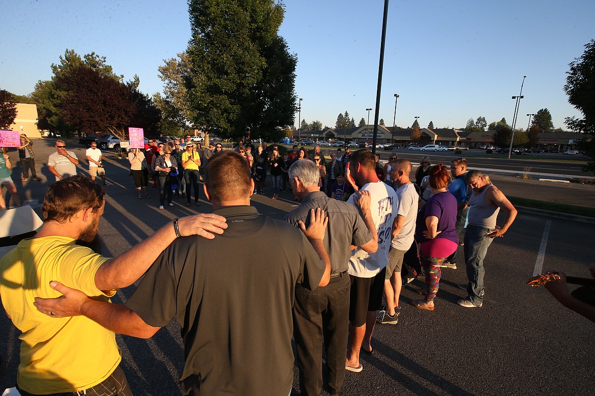 People pray for Pastor Paul Van Noy in a parking lot across the street from Kootenai Health on Wednesday.