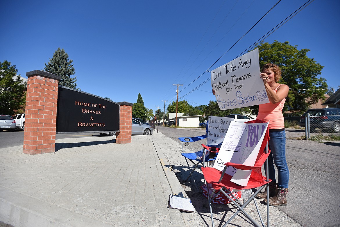 Jess Micklewright holds signs outside Flathead High School on Thursday, Sept. 10. Micklewright said she and others will be protesting outside Flathead Valley schools in the coming weeks in hopes that more family members will be permitted to attend sporting events. (Casey Kreider/Daily Inter Lake)