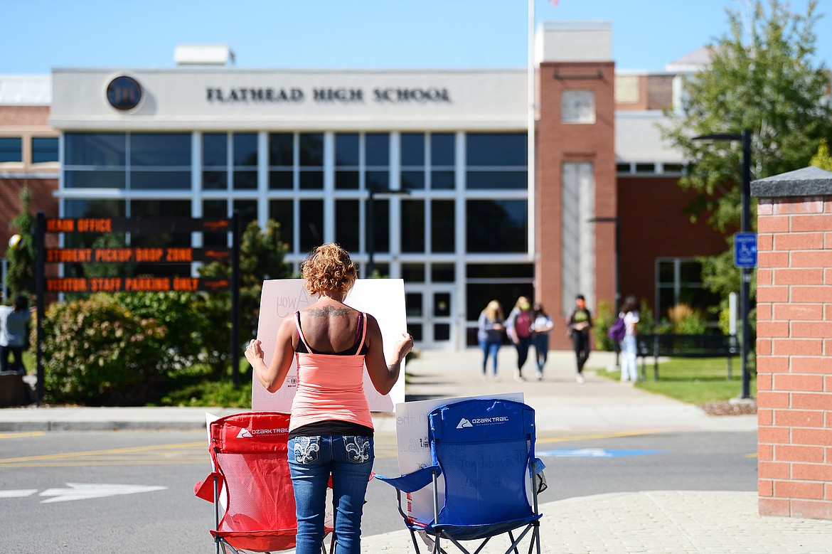 Jess Micklewright holds signs outside Flathead High School on Thursday, Sept. 10. Micklewright said she and others will be protesting outside Flathead Valley schools in the coming weeks in hopes that more family members will be permitted to attend sporting events. (Casey Kreider/Daily Inter Lake)