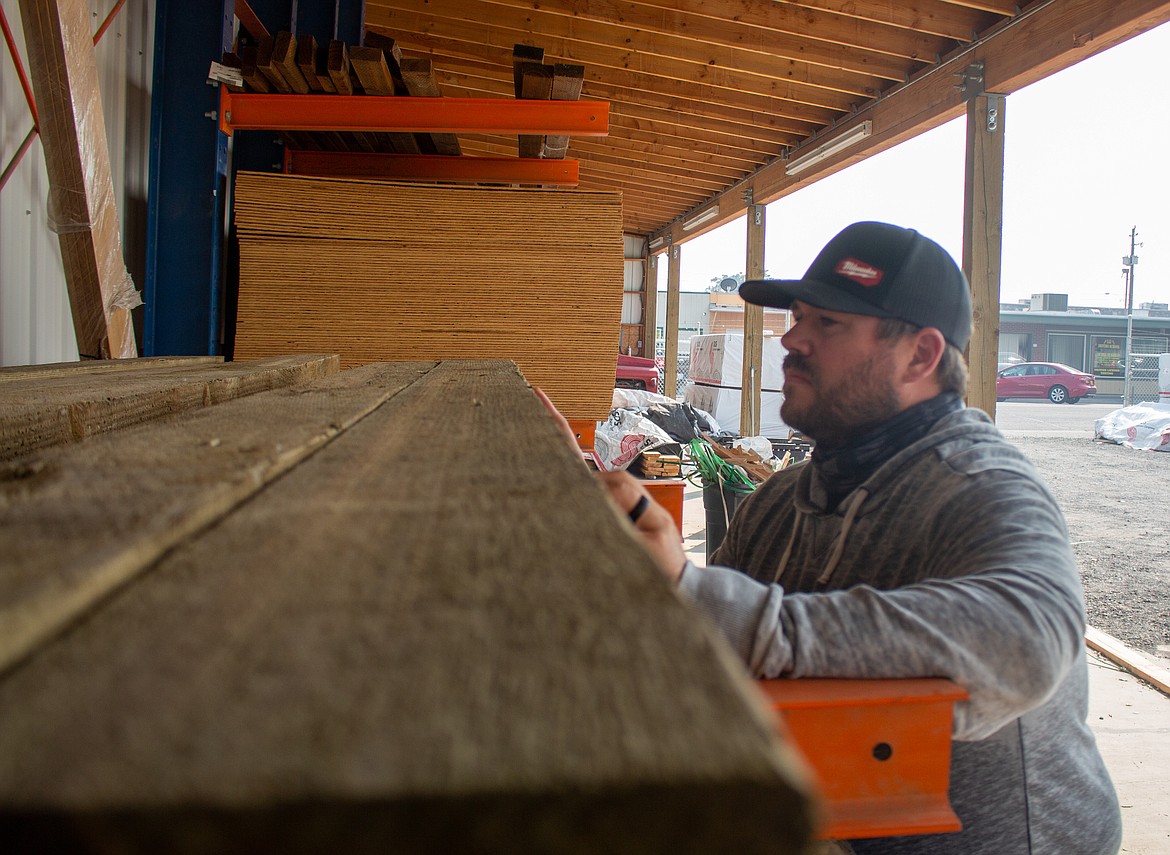 Jeremy Sewall, store manager at Quincy Hardware & Lumber, looks over some of the lumber in their yard behind the store on Wednesday afternoon.