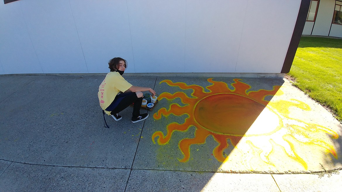 Plains High School junior Johnathan McPhee shows off an art project he did outside the gym. McPhee is in Kristen Cole's art class. The teacher wanted something that gets the kids outside in nice weather and gives them a positive setting for their art expression. (Chuck Bandel/Valley Press)