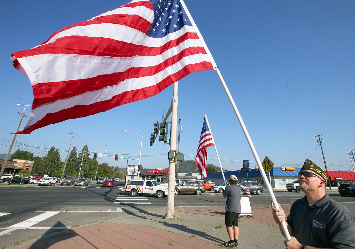 Terry Alling and son RJ Alling hold American flags at Fourth and Appleway on Friday afternoon.
