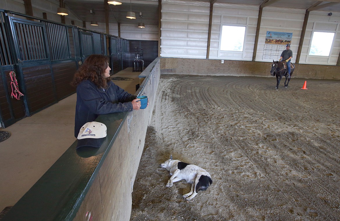 Cydie Wiltsie watches as her dog Walter sleeps and Randy Voll rides Odina at Running W Therapeutic Riding Center.