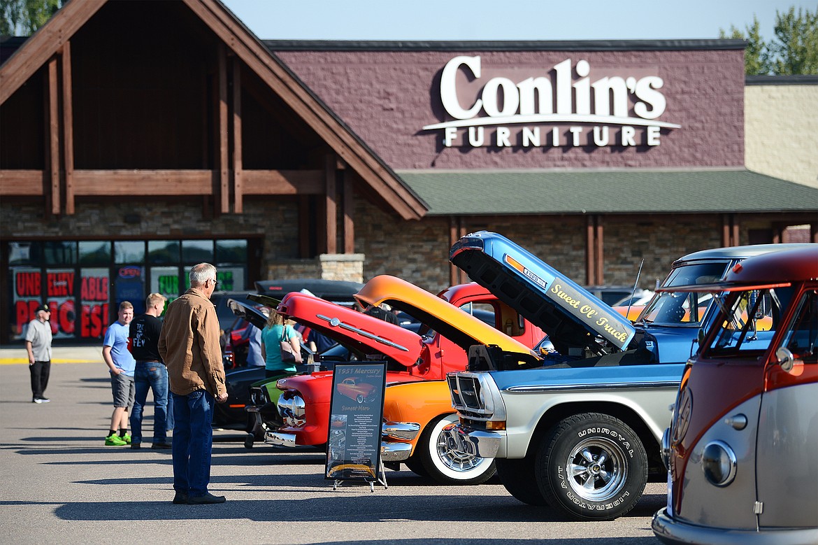 Attendees check out other vehicles after driving through the Evergreen Show ’N Shine virtual car show at Conlin’s Furniture on Saturday.  (Casey Kreider/Daily Inter Lake)