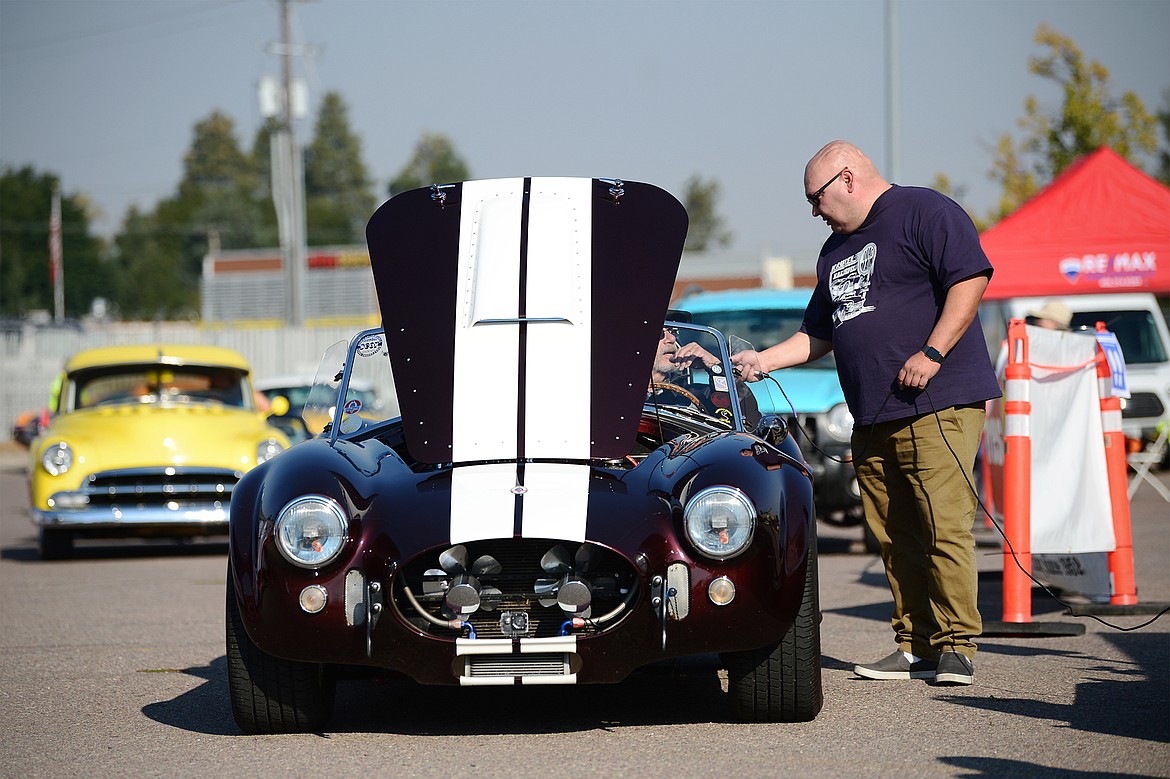 Monte Klindt, right, co-owner of Performance Heating & Air in Evergreen and a co-organizer of Kruise Kalispell, speaks with Fred Hamilton as he drives his 1966 Shelby Cobra SC through the Evergreen Show ’N Shine virtual car show at Conlin’s Furniture on Saturday.  (Casey Kreider/Daily Inter Lake)