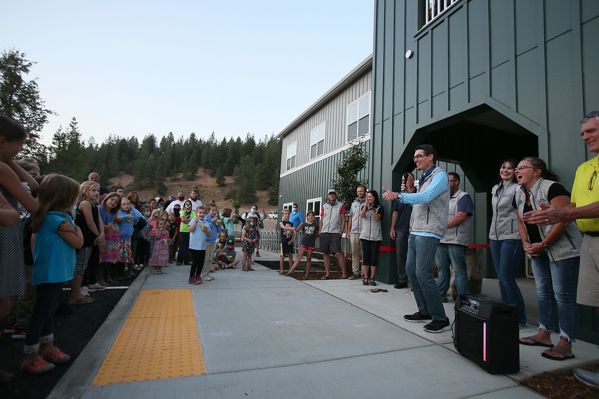 Hayden Canyon Charter board member Joshua Dahlstrom, with the mic, reacts Friday evening as a little boy yells "Yay!" in response to the good news that the school will open Sept. 21.