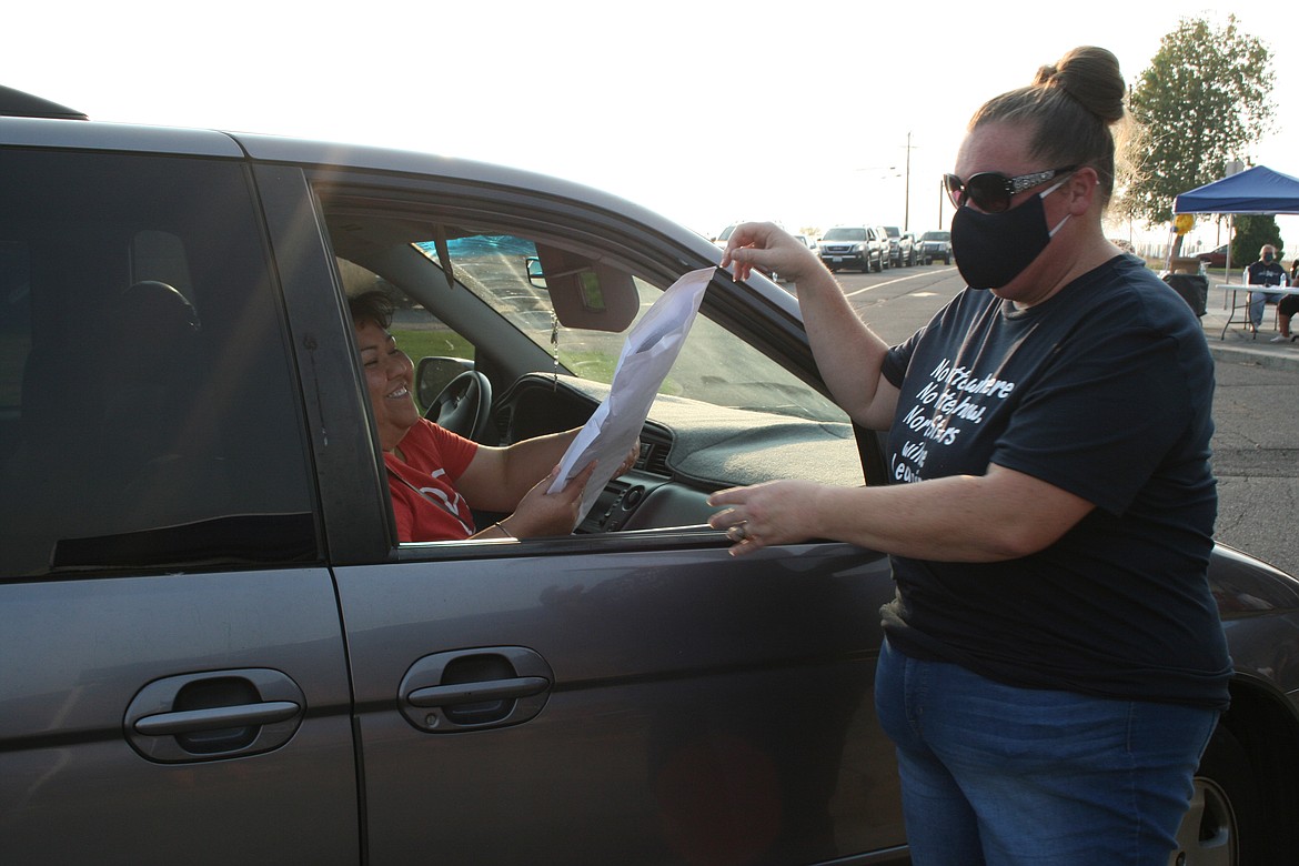 Sheryl Cassella hands out a computer during the drive-through distribution Friday at North Elementary School. School started today for all Moses Lake students.