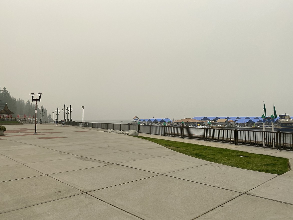 Pedestrians walk by the nearly invisible Lake Coeur d'Alene landscape Monday afternoon. (MADISON HARDY/Press)