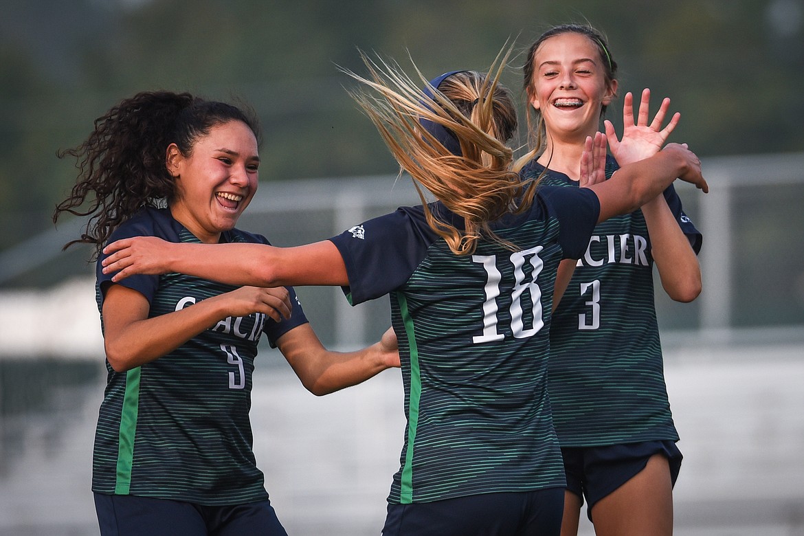 Glacier's Madison Becker (18) celebrates with teammates Ady Powell (9) and Reagan Brisendine (3) after Becker's first-half goal against Flathead during crosstown soccer at Legends Stadium on Tuesday. (Casey Kreider/Daily Inter Lake)